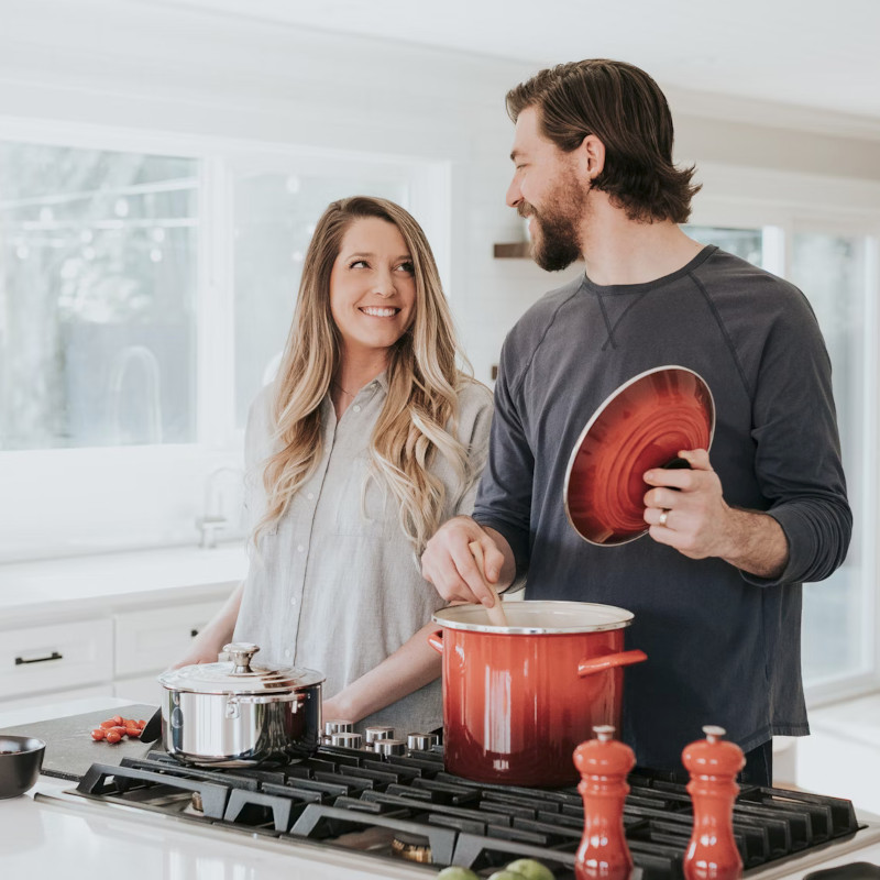 Smiling couple cooking together in a bright kitchen.